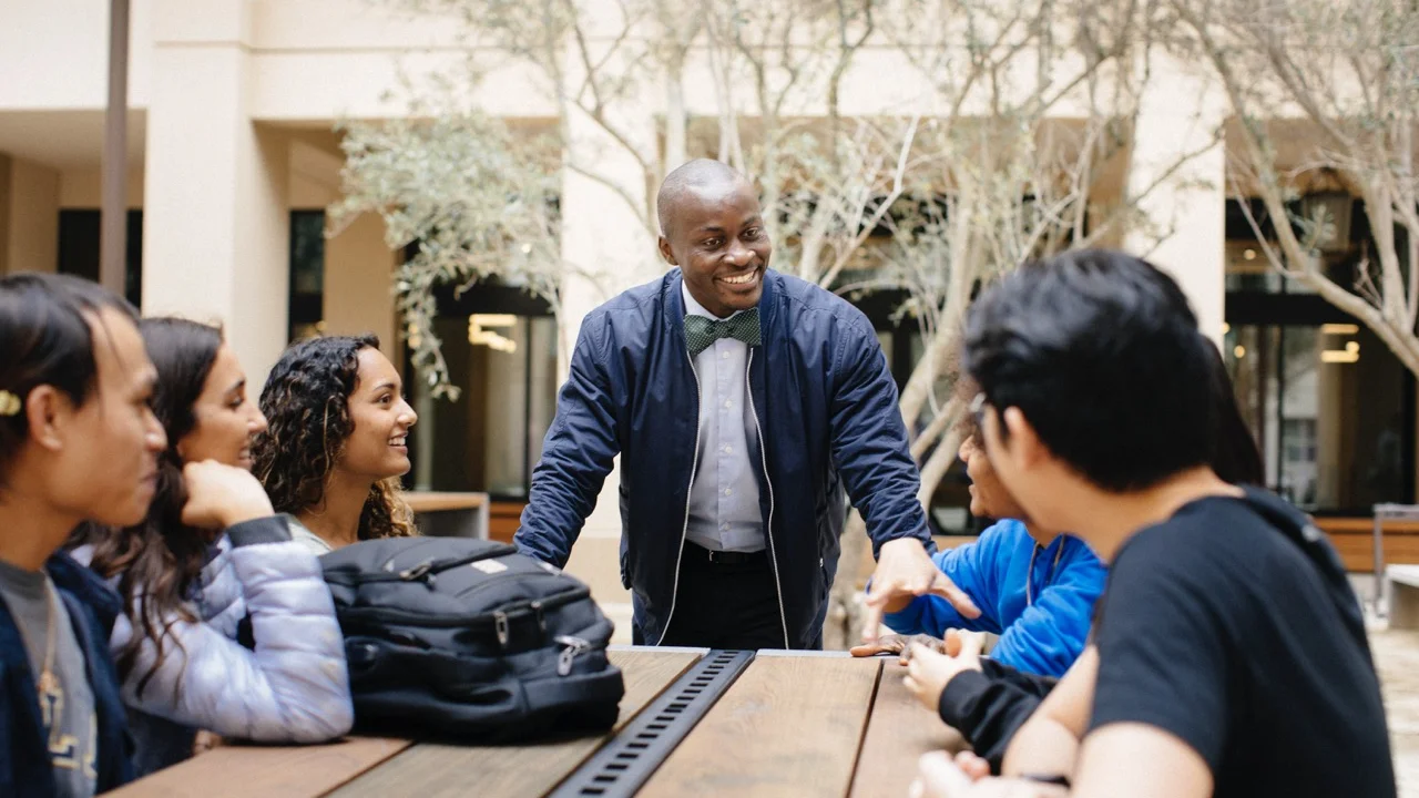 People in the UCLA community talk and smile around an outdoor table.